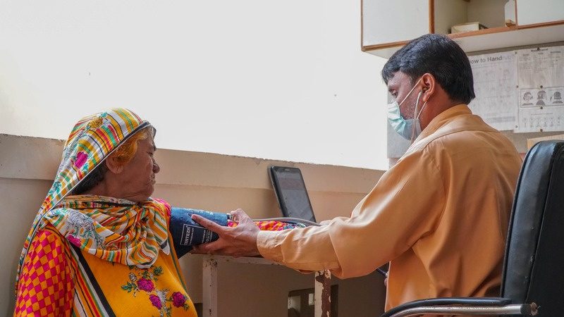 A SINA clinician checks an elderly patient's blood pressure